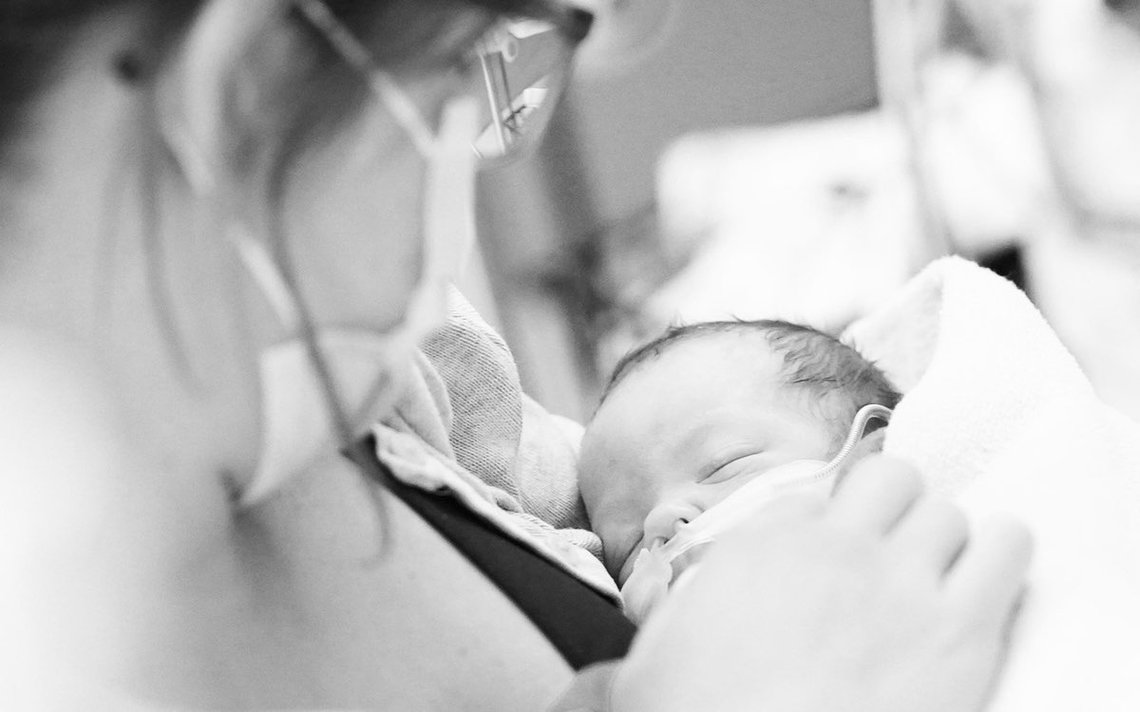 Abbildung: Fachpflegekraft mit Neugeborenem im Arm